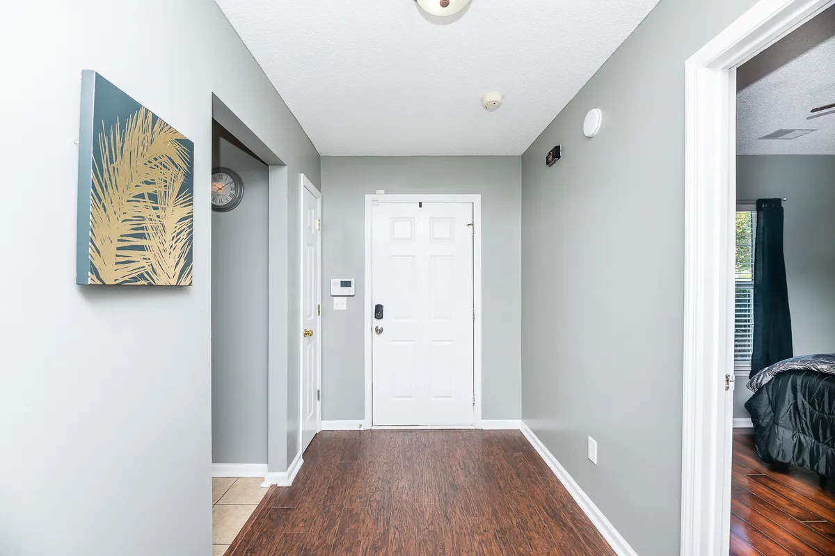This interior view captures the front door flanked by wall art and a clock, presenting a neat and stylish entrance. The scene evokes the feeling of greeting guests and the ease of returning home, underscoring the importance of first impressions and the practical flow of the entryway.