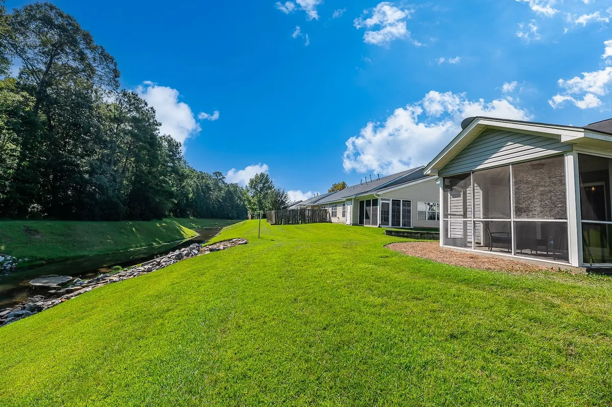 A tranquil exterior view of the building facade, expansive lawn, and a gentle stream under a wide sky. The area evokes a sense of peace and relaxation, ideal for unwinding after a lively evening in the city.