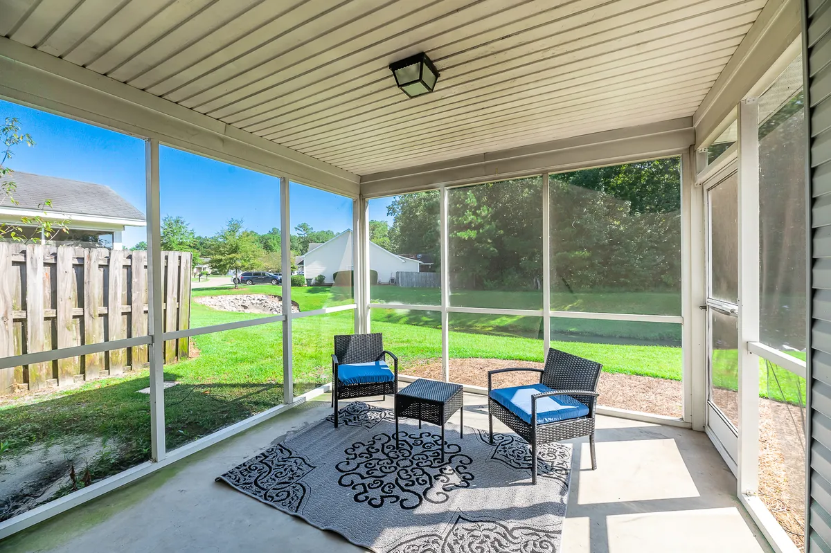 A glass-enclosed seating area with stylish blue-cushioned chairs, a decorative rug, and panoramic outdoor views. The space feels airy, serene, and is an ideal spot for relaxing, reading, or taking in the surrounding scenery.
