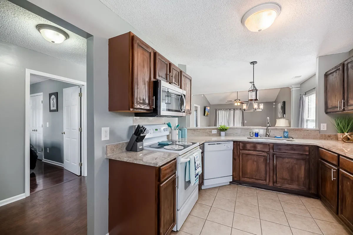 This image captures a spacious kitchen with a central island, wooden cabinets, and modern stainless steel appliances. The dining area is visible in the background, subtly connecting both spaces. The setup is inviting and clearly designed for both cooking and gathering, emphasizing functionality and togetherness.