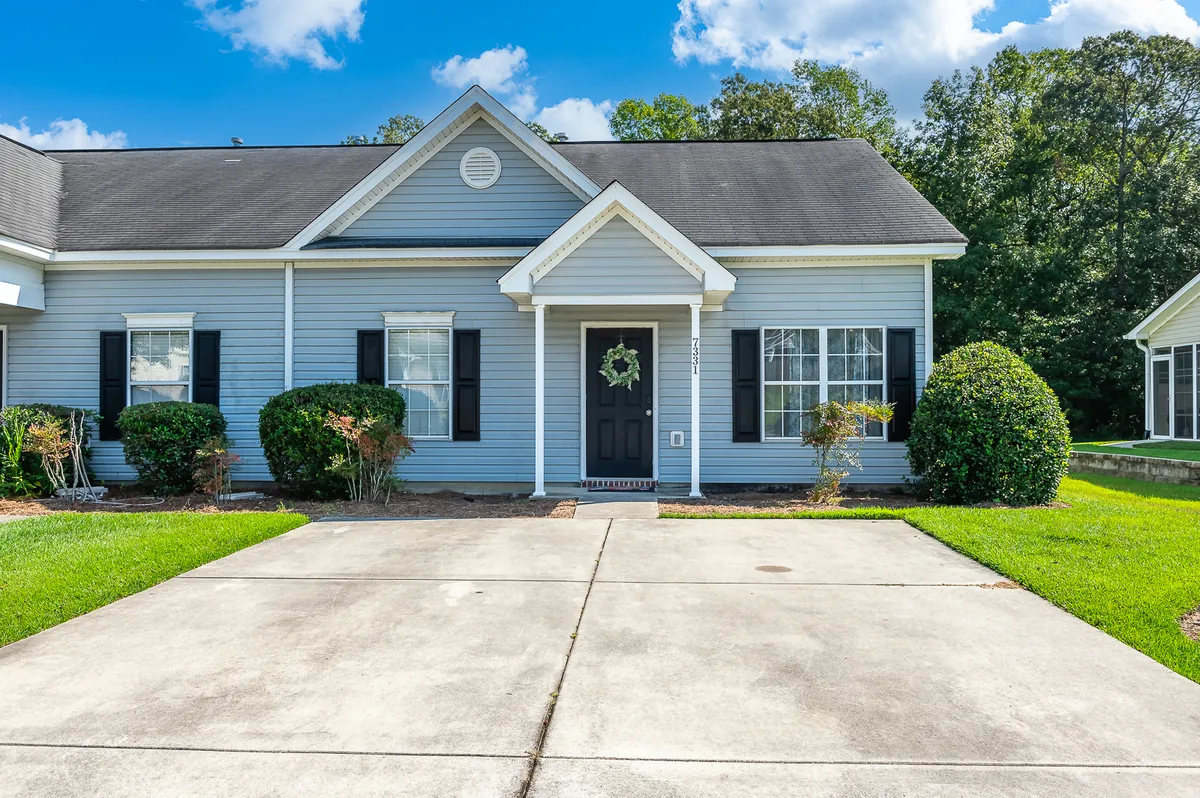 A welcoming front entrance is framed by well-kept landscaping, wide windows, and a cheerful front door. The scene suggests a friendly, safe environment where families can easily come and go, welcoming visitors or heading out for local adventures.